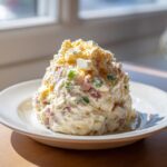 A generous scoop of creamy ham salad recipe mixed with diced ham, green peppers, and topped with crumbled egg yolk.