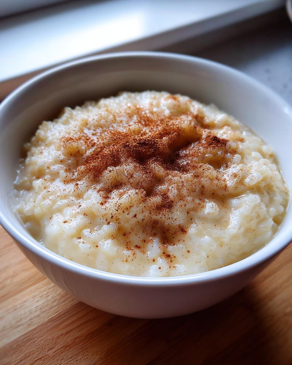 Close-up of creamy rice pudding in a white bowl, generously sprinkled with cinnamon.