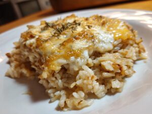 Close-up of a serving of french onion butter rice topped with melted, browned cheese and dried herbs.