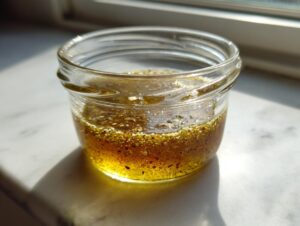 Close-up of homemade salad dressing in a small glass jar, showing separation of oil and spices.
