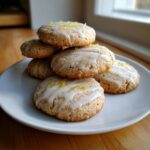 A stack of freshly baked Earl Grey cookies drizzled with white icing and topped with bright yellow lemon zest.