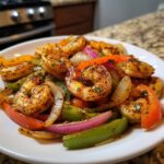 Close-up of perfectly seasoned shrimp fajitas featuring grilled shrimp, red onion, and colorful bell peppers.