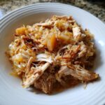 Close-up of shredded pork and sauerkraut mixture, featuring tender pulled pork mixed with caramelized cabbage, served in a white bowl.