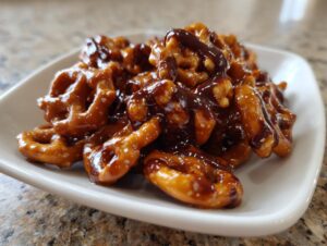 A close-up of crunchy pretzels coated in shiny toffee and drizzled with dark chocolate, making amazing toffee pretzels.
