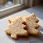 Close-up of three tree-shaped vegan sugar cookies dusted generously with sparkling sugar.