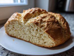 A freshly baked loaf of soda bread, cut in half to show the soft, airy interior texture.