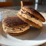 Two decadent tiramisu cookies sandwiched with thick, creamy filling and dusted with cocoa powder.