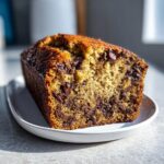A close-up view of a freshly baked chocolate chip banana bread loaf showing its moist texture and melted chocolate chips.