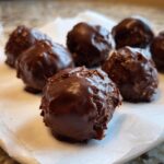 Several rich, dark chocolate rice krispie balls resting on white parchment paper.
