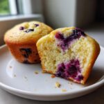 Close-up of a cottage cheese blueberry muffin cut in half showing the moist, yellow crumb packed with juicy blueberries.