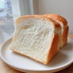Close-up of two thick slices of incredibly soft Japanese milk bread on a white plate.