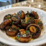 Close-up of glossy, sautéed garlic butter mushrooms topped with fresh parsley and minced garlic.