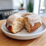 Close-up of a glazed cake donut cut in half, revealing its fluffy interior texture.