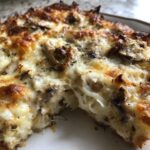 Close-up of a cheesy, bubbly keto garlic mushroom chicken casserole with melted cheese pulling away.