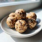 A stack of homemade no bake protein balls studded with oats and chocolate chips on a small plate.