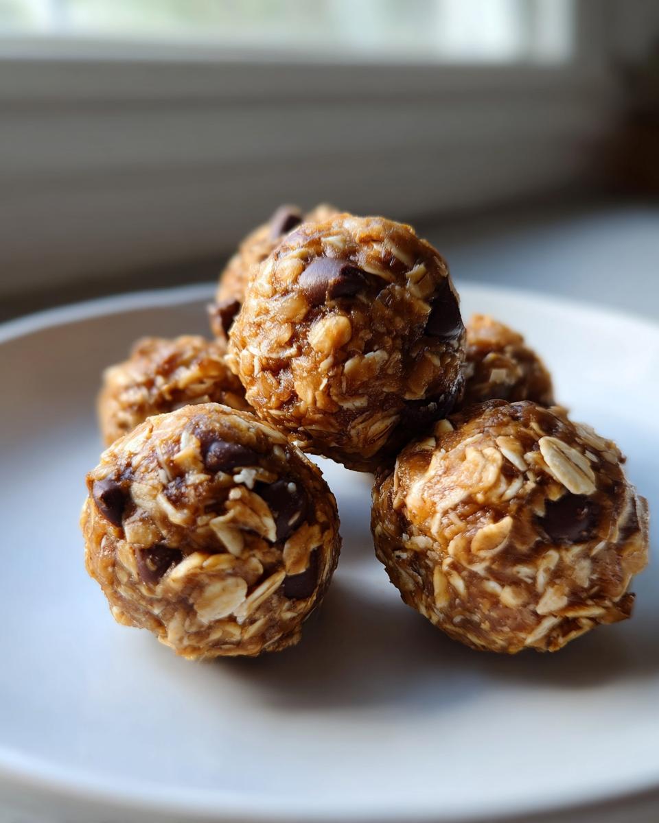 A small stack of delicious no bake protein balls studded with oats and chocolate chips on a white plate.