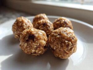 A close-up shot of several homemade no bake protein balls made with oats and dried fruit on a white plate.
