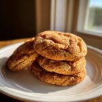 A stack of four soft, chewy cinnamon cookies generously coated in cinnamon sugar, sitting on a white plate.