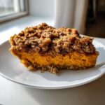 A close-up slice of rich orange sweet potato casserole topped with a thick, crunchy brown sugar pecan streusel.