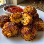 Close-up of golden brown parmesan mozzarella cheese bites, one is broken open showing melted cheese pull.