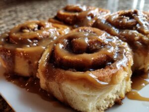 Close-up of gooey banana bread cinnamon rolls generously topped with a rich caramel glaze.