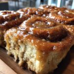 Close-up of soft, fluffy banana bread cinnamon rolls generously topped with a sticky, gooey caramel-like glaze.