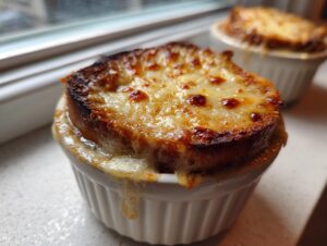 Close-up of a perfectly broiled, cheesy crouton topping on a bowl of rich french onion soup.