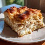 A thick, golden-brown slice of chicken crescent roll casserole filled with shredded chicken and creamy sauce.