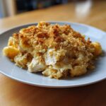 A serving of creamy chicken pasta casserole topped with a thick, golden-brown breadcrumb crust.