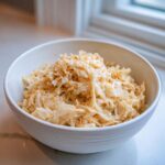 Close-up of creamy Cabbage Alfredo served in a white bowl on a light countertop.