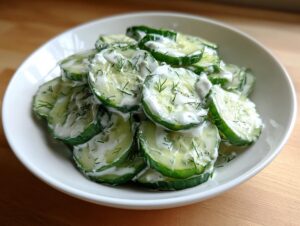 Close-up of a fresh cucumber salad made with sliced cucumbers, creamy dressing, and fresh dill.