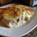 A close-up serving of creamy Scalloped Potatoes and Ham, showing layers of potato, ham, and a cheesy, bubbly topping.