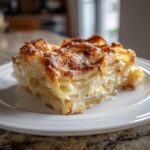 A close-up of a rich, cheesy slice of scalloped potatoes with a golden-brown, bubbly top.