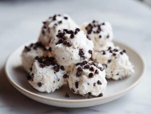 A stack of delicious frozen greek yogurt peanut butter bites topped with mini chocolate chips on a light plate.