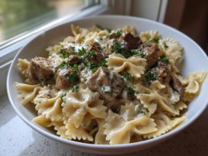 Close-up of a white bowl filled with garlic butter chicken with bowtie pasta coated in a creamy sauce and garnished with parsley.
