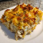 A close-up of a serving of cheesy green chile chicken and rice casserole with a golden, bubbly top.