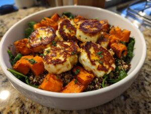 Close-up of a vibrant halloumi sweet potato bowl featuring seared halloumi cheese, roasted sweet potatoes, and quinoa.