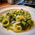 Close-up of perfectly cooked braised leeks, sliced into rings and glistening in a light sauce.