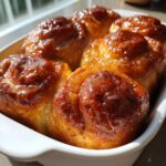 Close-up of freshly baked, golden brown milk bread honey buns covered in a shiny honey glaze.
