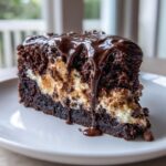 Close-up of a rich slice of Mississippi mud cake featuring dark chocolate cake, creamy filling, and dripping chocolate fudge frosting.