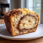 Close-up of a thick slice of moist apple bread featuring a rich cinnamon swirl filling.