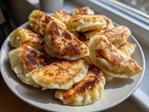 A plate piled high with freshly pan-fried Cabbage Dumplings, showing golden-brown, crispy edges.