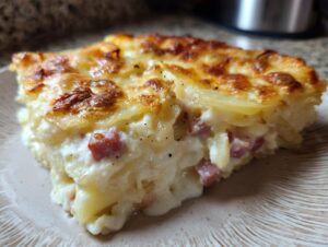 A close-up slice of creamy, cheesy Scalloped Potatoes and Ham with a golden-brown top.
