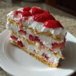 A decadent slice of strawberry cream cheese icebox cake layered with graham crackers, cream, and fresh strawberries.