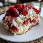 A generous slice of Strawberry Shortcake Trifle showing layers of cake, whipped cream, and macerated strawberries on a white plate.