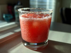 A frosty glass filled with a bright red Watermelon Margarita, featuring a thick sugar or salt rim.