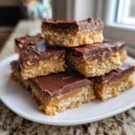 A close-up stack of homemade 3-layer toffee bars featuring a crumbly base, gooey caramel, and rich chocolate topping.