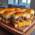 A row of freshly baked Cheeseburger sliders featuring seasoned ground beef and melted cheddar cheese on soft buns.