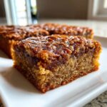A close-up, appetizing shot of a square of rich, gooey Pecan blondies with a thick, caramelized pecan topping.