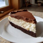 A decadent slice of Chocolate haupia pie showing a dark chocolate crust, white haupia filling, and chocolate topping.